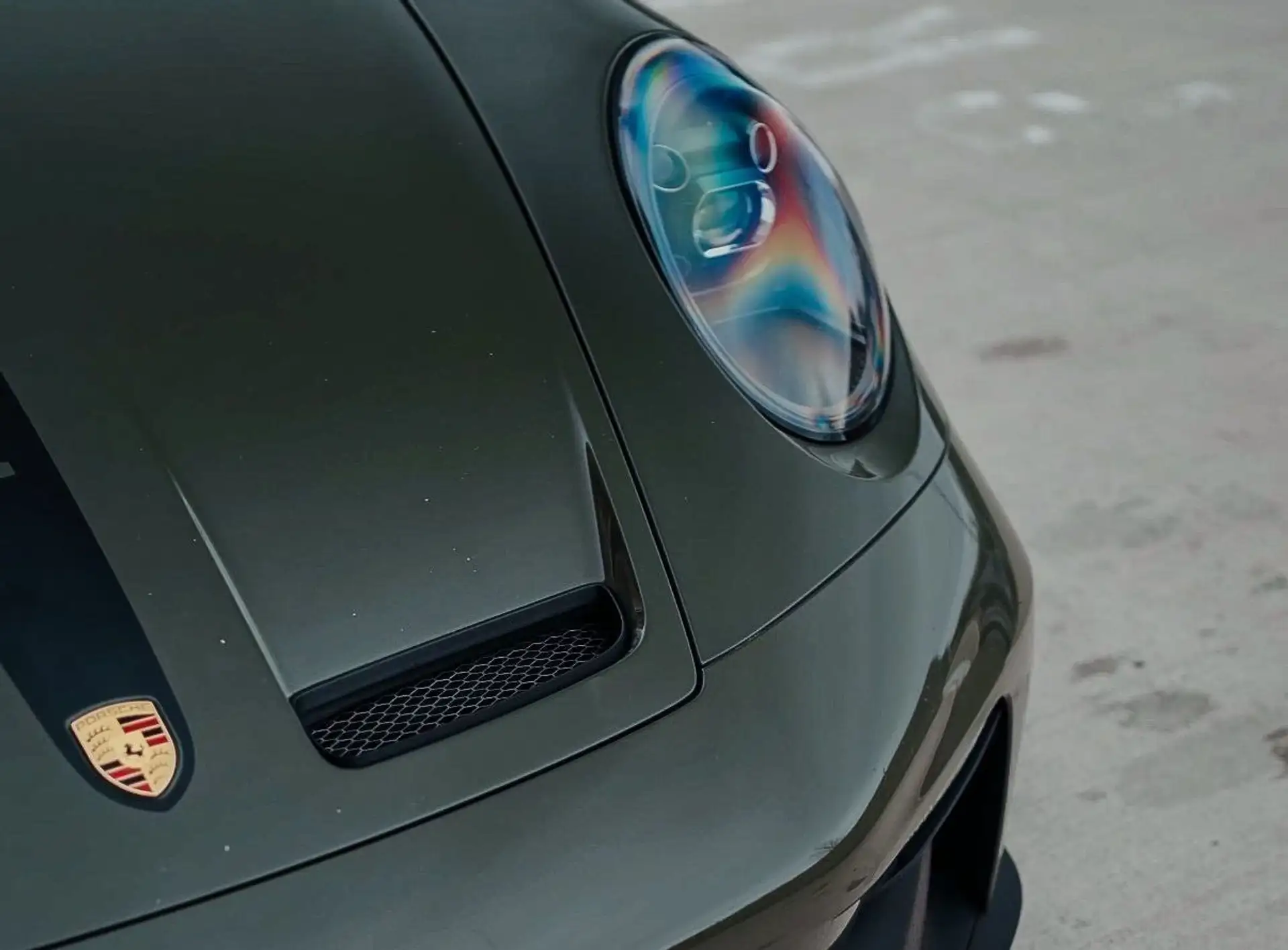 The headlights of our olive green Porsche GT3 in a close-up photo. 